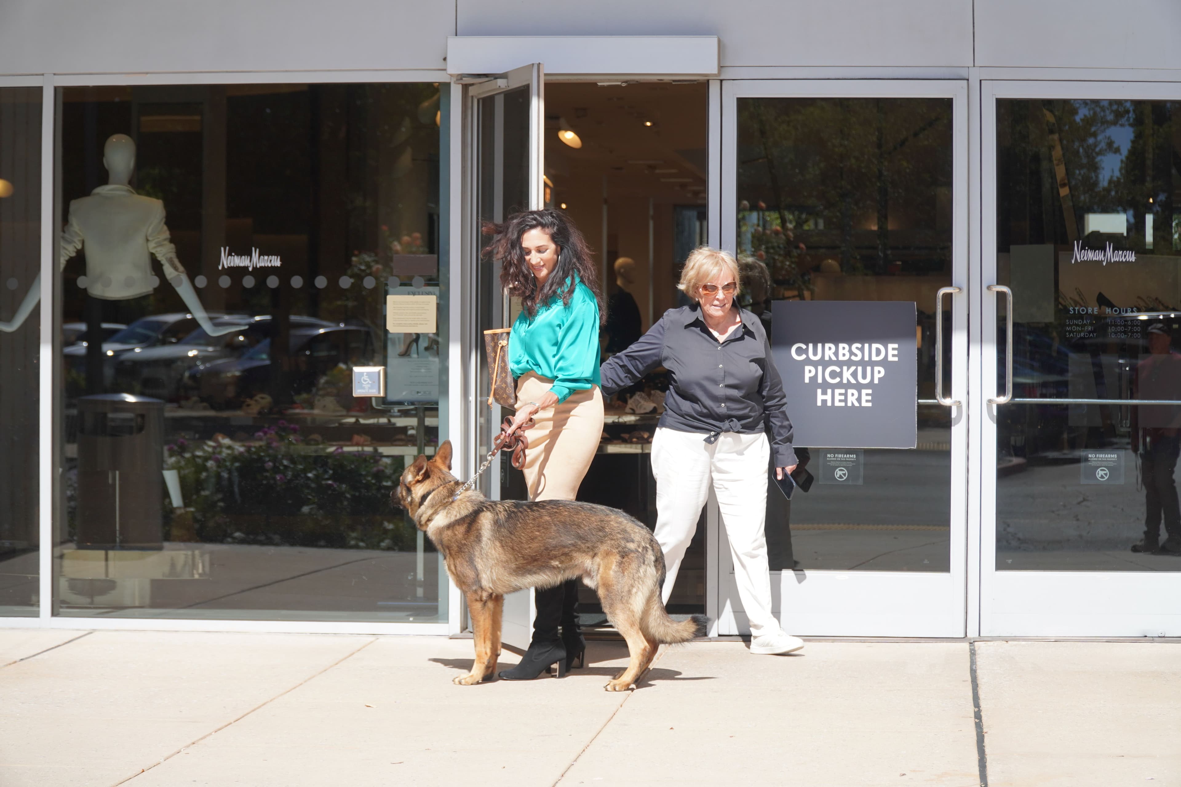 A handler walking a German Shepherd protection dog outside a storefront.
